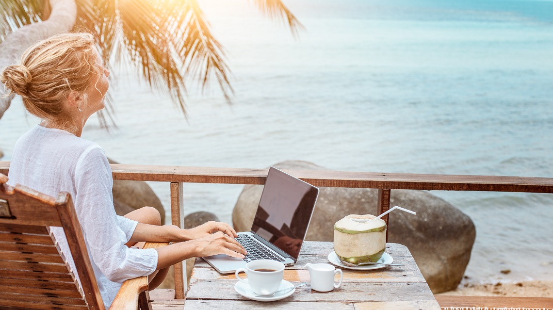Young woman working on laptop with coffee and young coconut